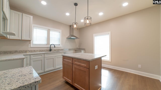 kitchen featuring sink, wall chimney exhaust hood, a kitchen island, dark hardwood / wood-style flooring, and white cabinetry