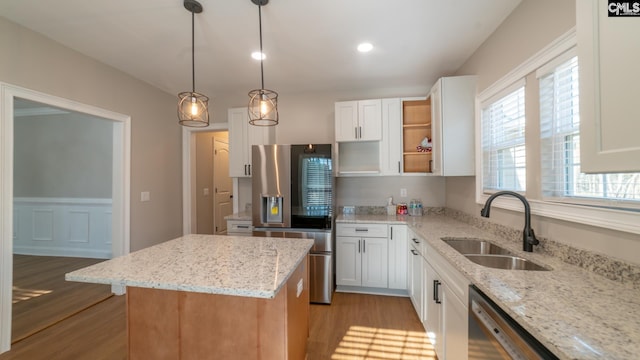 101 Dinkins Place Rd, Blythewood, SC 29130 - kitchen featuring appliances with stainless steel finishes, a sink, light wood finished floors, a kitchen island, and white cabinetry