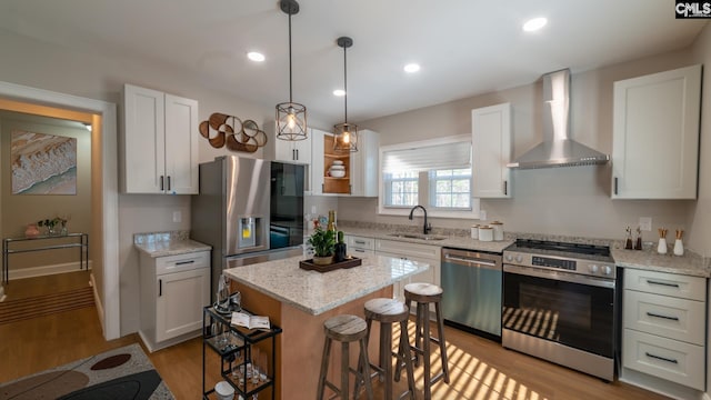 101 Dinkins Place Rd, Blythewood, SC 29130 - kitchen featuring stainless steel appliances, wall chimney exhaust hood, a sink, light wood-type flooring, and a kitchen breakfast bar