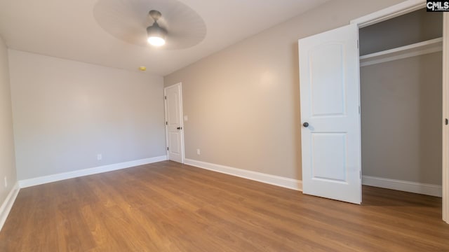 unfurnished bedroom featuring a closet, hardwood / wood-style floors, and ceiling fan