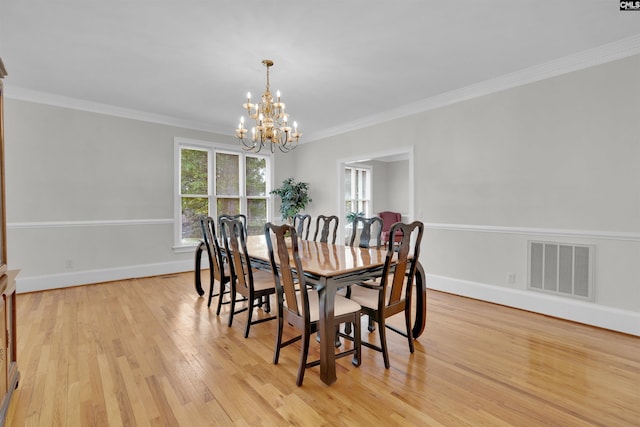 dining room with ornamental molding, light hardwood / wood-style flooring, and an inviting chandelier