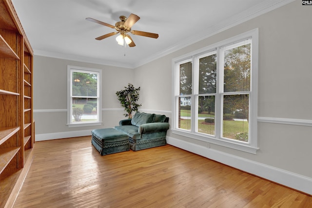 living area with ornamental molding, light hardwood / wood-style floors, and ceiling fan