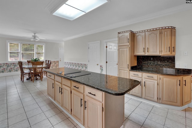 kitchen with black electric stovetop, a kitchen island, ceiling fan, dark stone countertops, and light brown cabinets