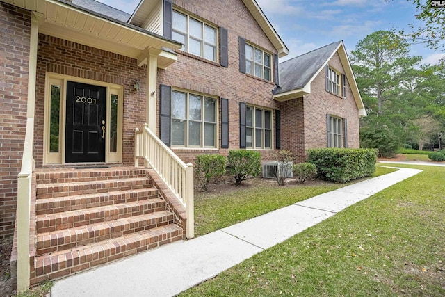 property entrance with cooling unit and a lawn