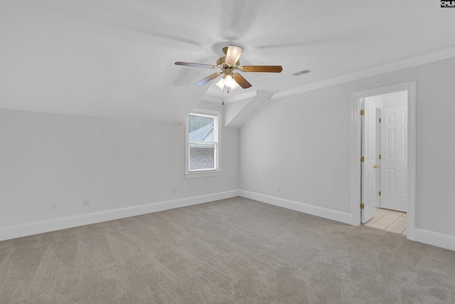 additional living space featuring lofted ceiling, light carpet, a textured ceiling, and ceiling fan