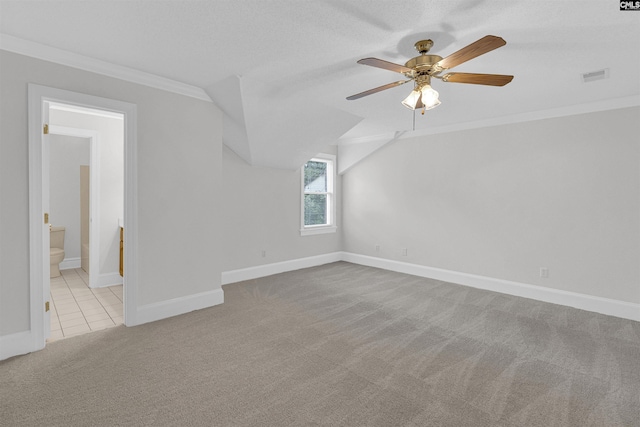 bonus room with a textured ceiling, light colored carpet, and ceiling fan