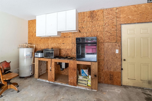 kitchen with white cabinetry, oven, water heater, and concrete flooring