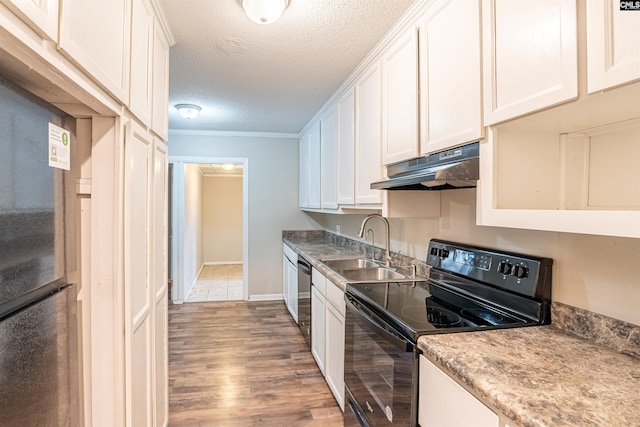 kitchen with light hardwood / wood-style flooring, white cabinets, black appliances, and a textured ceiling