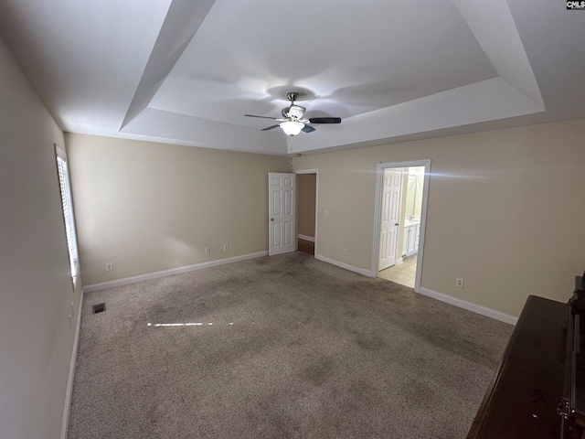 carpeted spare room with a tray ceiling and ceiling fan