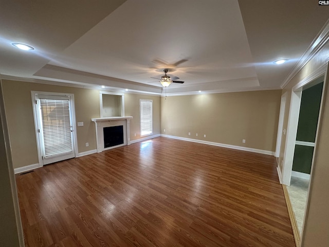 unfurnished living room with ornamental molding, a tray ceiling, wood-type flooring, and ceiling fan