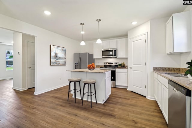 kitchen with pendant lighting, white cabinets, stainless steel appliances, and dark hardwood / wood-style floors