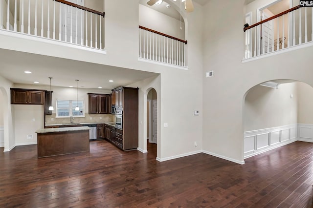 unfurnished living room featuring sink, dark wood-type flooring, and a high ceiling