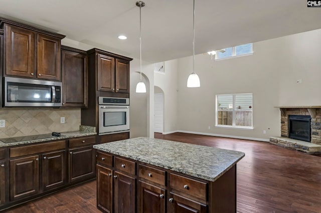 kitchen with dark brown cabinets, dark hardwood / wood-style floors, stainless steel appliances, and hanging light fixtures