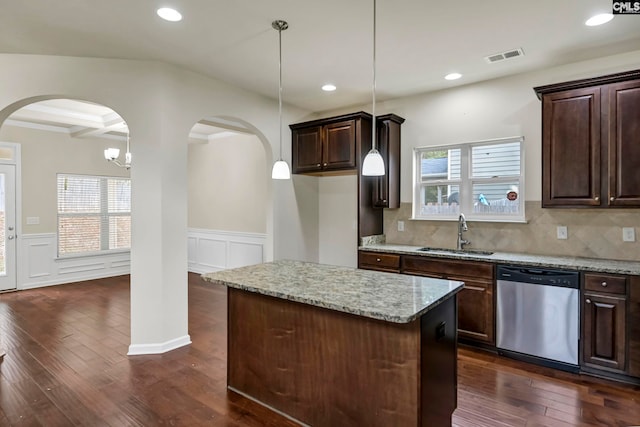 kitchen with dishwasher, a kitchen island, sink, decorative light fixtures, and light stone counters