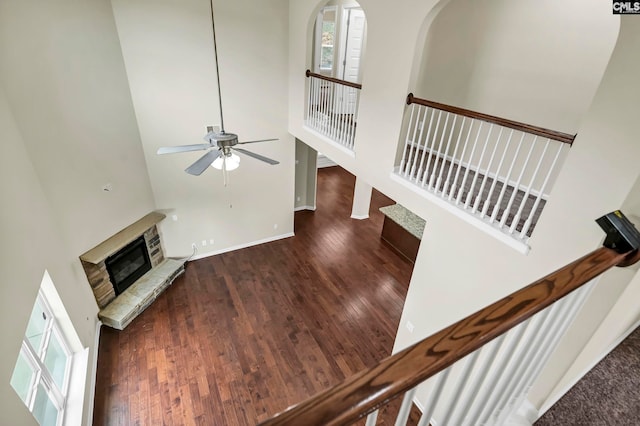 living room with a fireplace, dark wood-type flooring, a high ceiling, and ceiling fan