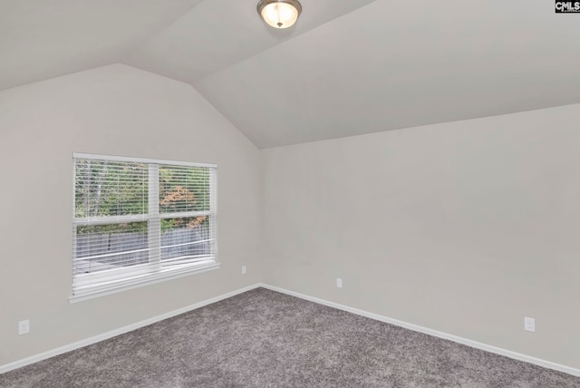 carpeted empty room with vaulted ceiling