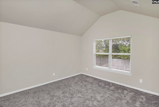 carpeted spare room with vaulted ceiling