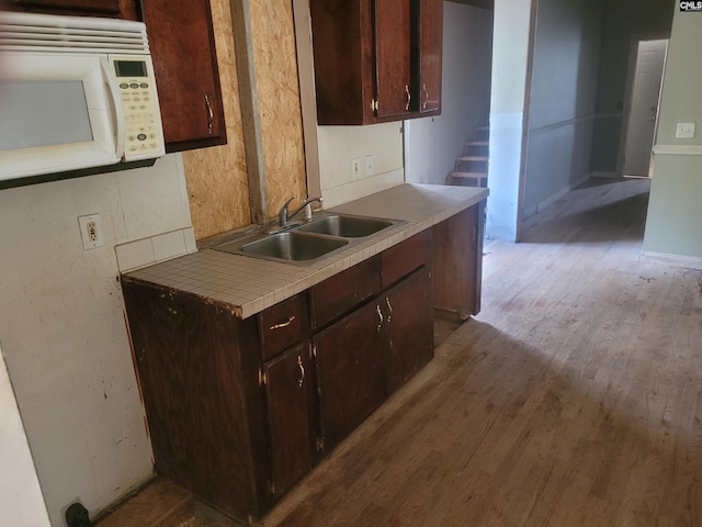 kitchen with sink, dark brown cabinets, and light wood-type flooring