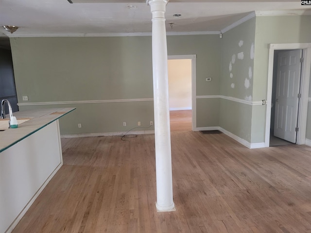 kitchen featuring ornate columns, ornamental molding, and light hardwood / wood-style flooring