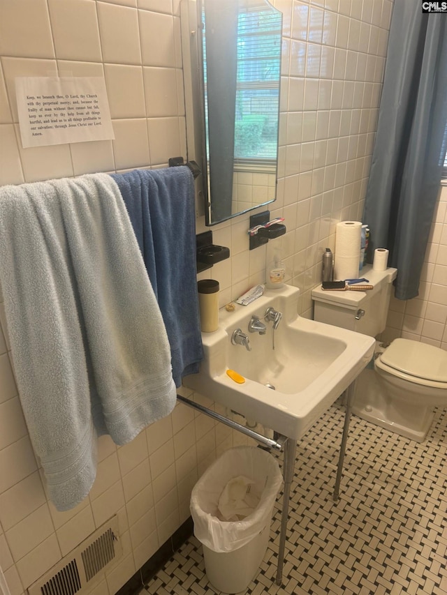 bathroom featuring toilet, tile patterned floors, and tile walls