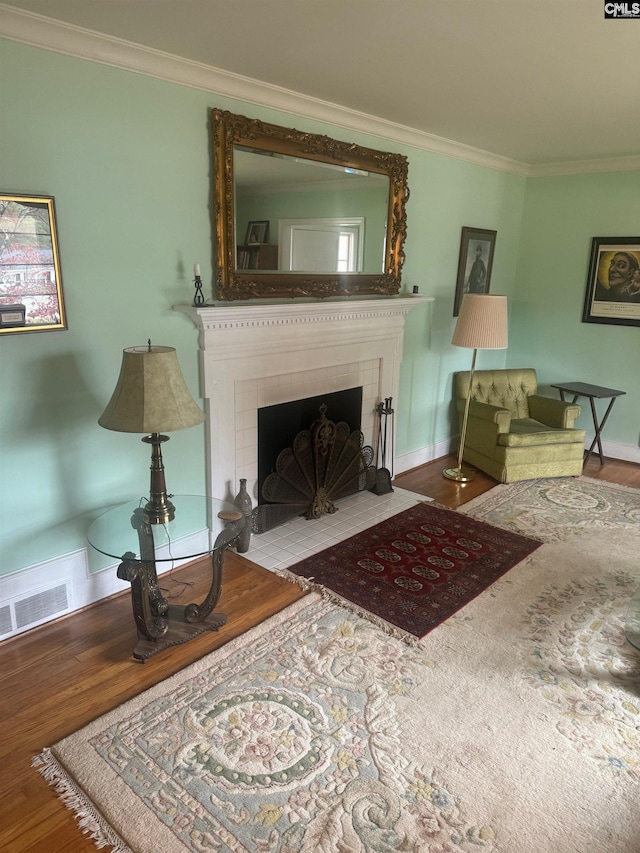 living room featuring ornamental molding, a fireplace, and hardwood / wood-style flooring