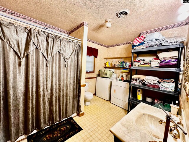 bathroom with a textured ceiling, washing machine and clothes dryer, toilet, vanity, and a shower with curtain