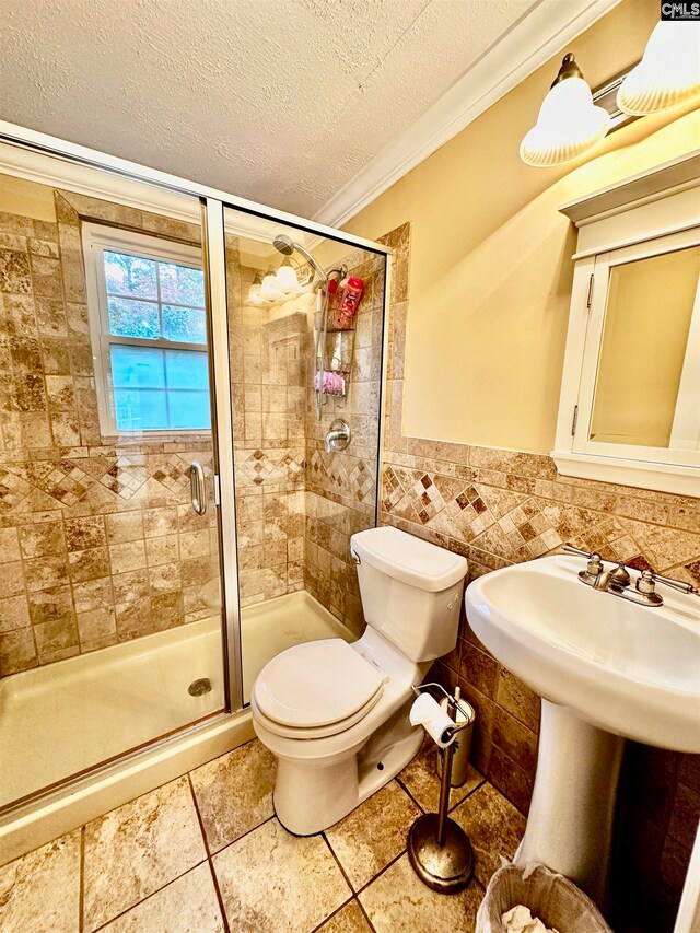 bathroom with a textured ceiling, toilet, walk in shower, ornamental molding, and tile patterned flooring