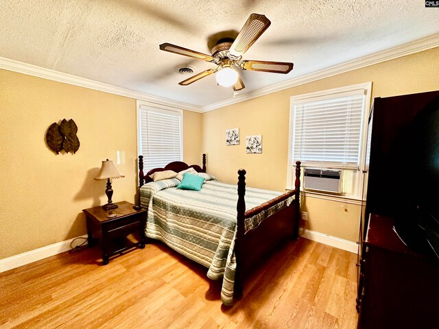 bedroom with ceiling fan, cooling unit, a textured ceiling, light wood-type flooring, and crown molding