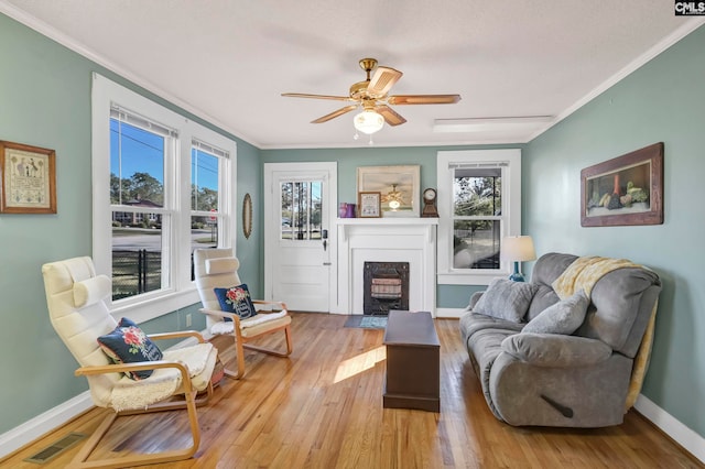 living room featuring a wealth of natural light, ornamental molding, and light hardwood / wood-style flooring