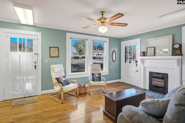 living room featuring crown molding, a textured ceiling, light wood-type flooring, and ceiling fan