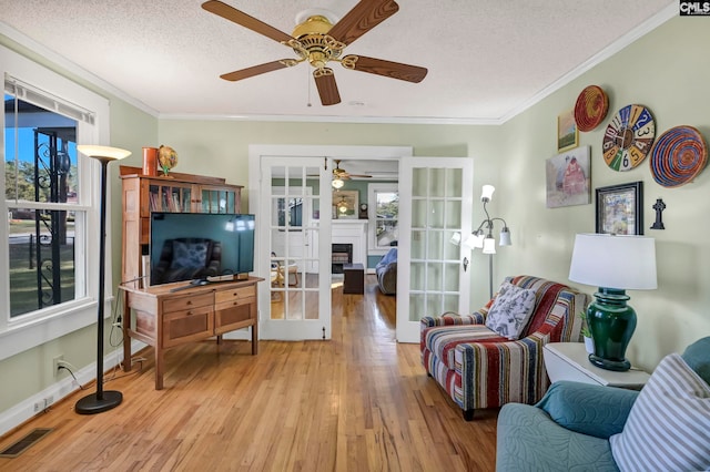 living room with french doors, crown molding, a textured ceiling, and light hardwood / wood-style floors