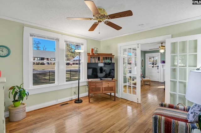 living room featuring crown molding, a textured ceiling, light hardwood / wood-style flooring, and ceiling fan