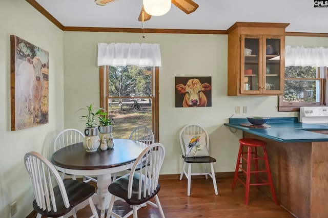 dining room with dark wood-type flooring, crown molding, and ceiling fan