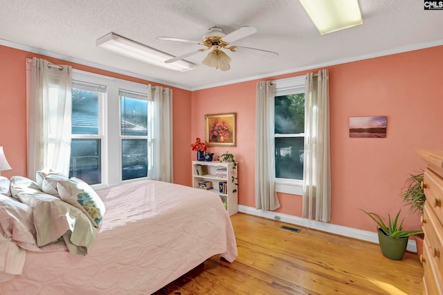 bedroom with crown molding, a textured ceiling, hardwood / wood-style flooring, and ceiling fan