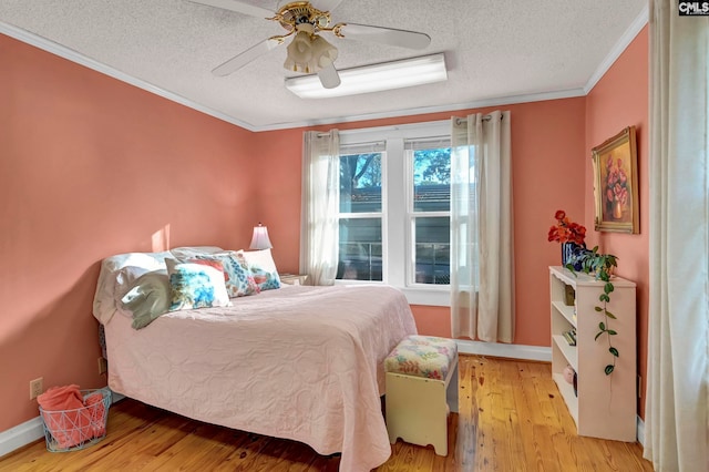 bedroom featuring ceiling fan, ornamental molding, a textured ceiling, and light wood-type flooring