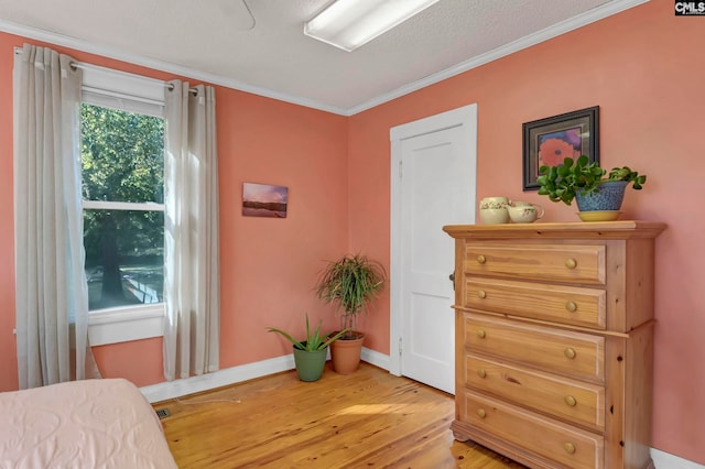 bedroom with ornamental molding, a textured ceiling, and wood-type flooring