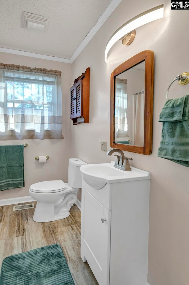 bathroom with hardwood / wood-style floors, a textured ceiling, toilet, ornamental molding, and vanity