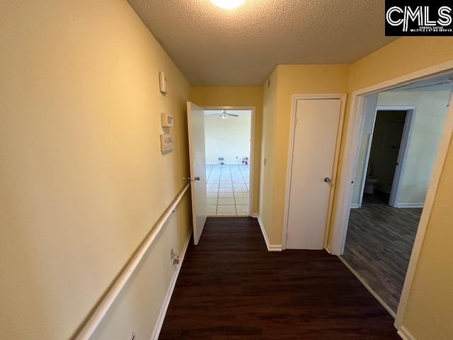 corridor featuring dark wood-type flooring and a textured ceiling