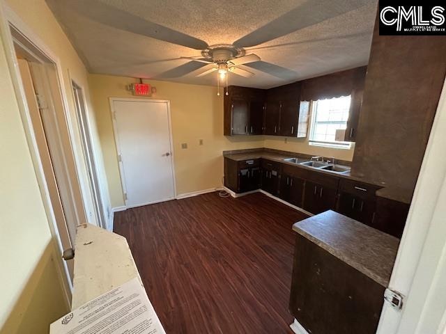 kitchen featuring dark wood-type flooring, a textured ceiling, dark brown cabinets, and sink