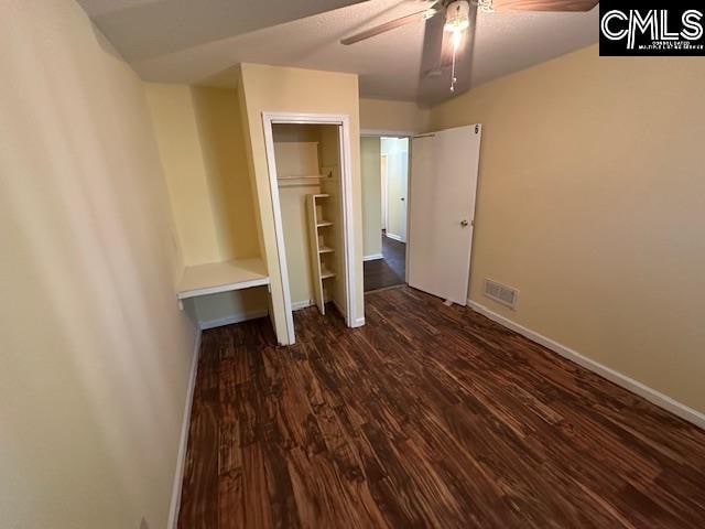 unfurnished bedroom with a closet, dark hardwood / wood-style floors, and ceiling fan