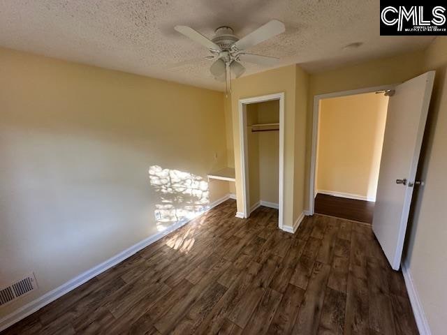 unfurnished bedroom with ceiling fan, a textured ceiling, and dark hardwood / wood-style flooring