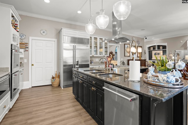 kitchen with a kitchen island with sink, sink, light hardwood / wood-style floors, crown molding, and stainless steel appliances