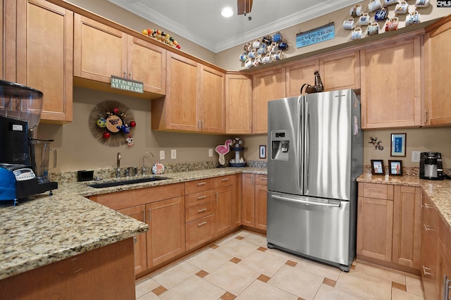 kitchen featuring light stone counters, ornamental molding, sink, and stainless steel fridge