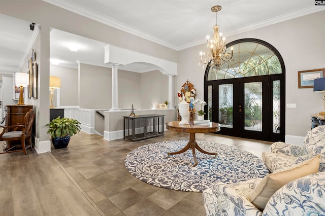 entrance foyer featuring french doors, ornate columns, hardwood / wood-style floors, crown molding, and an inviting chandelier