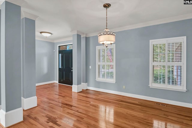 empty room with ornamental molding, hardwood / wood-style flooring, and plenty of natural light