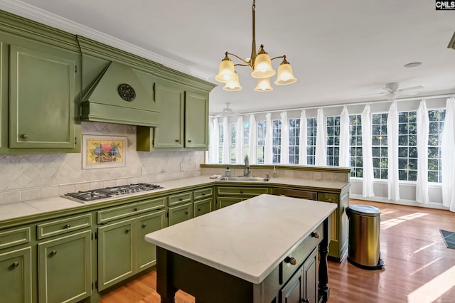 kitchen featuring sink, a center island, light hardwood / wood-style floors, custom exhaust hood, and stainless steel gas stovetop