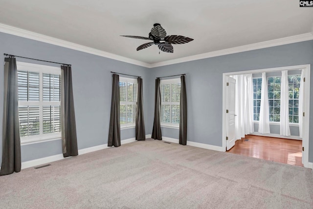 carpeted spare room featuring ornamental molding, ceiling fan, and plenty of natural light