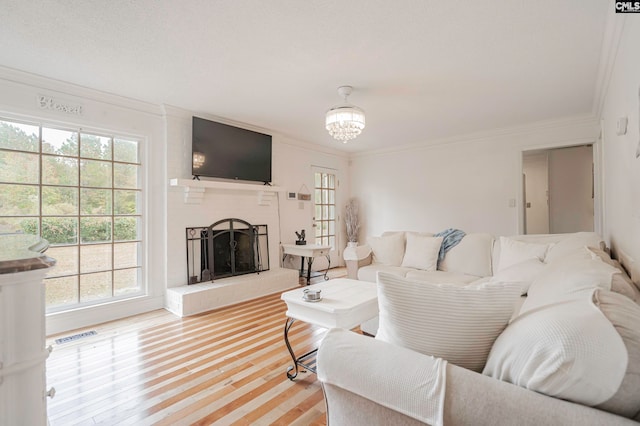 living room with ornamental molding, hardwood / wood-style flooring, plenty of natural light, and a brick fireplace