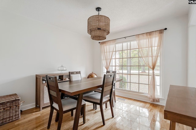 dining area with a textured ceiling and light hardwood / wood-style flooring