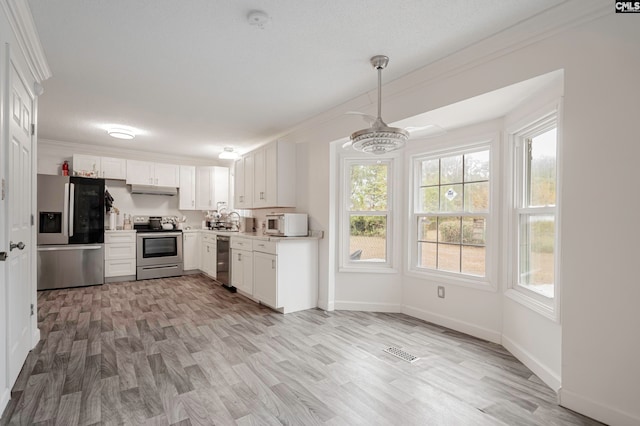 kitchen featuring light hardwood / wood-style flooring, stainless steel appliances, ornamental molding, sink, and white cabinets